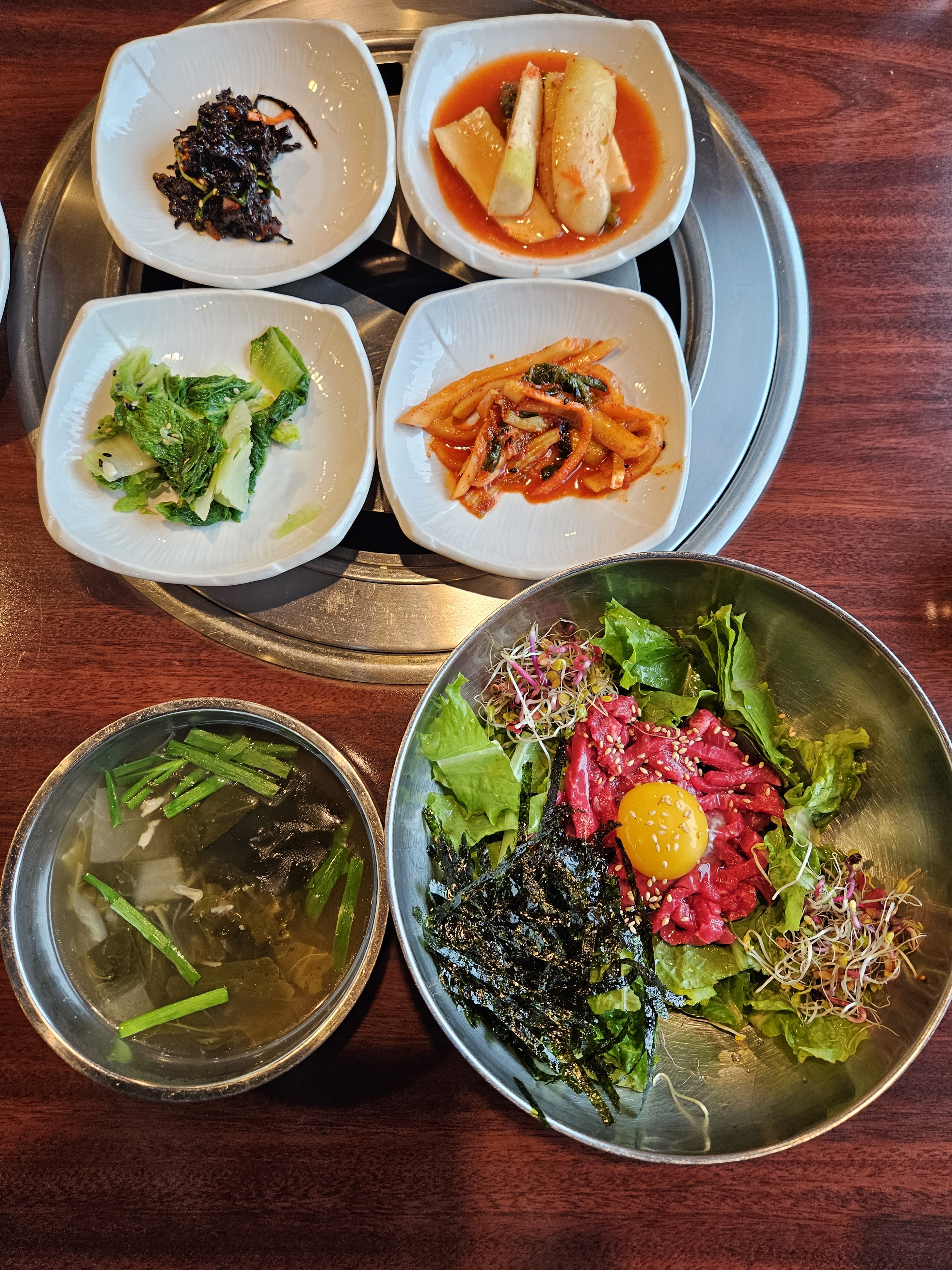 넓은 놋그릇에 담긴 비빔밥과 곁들임 국물