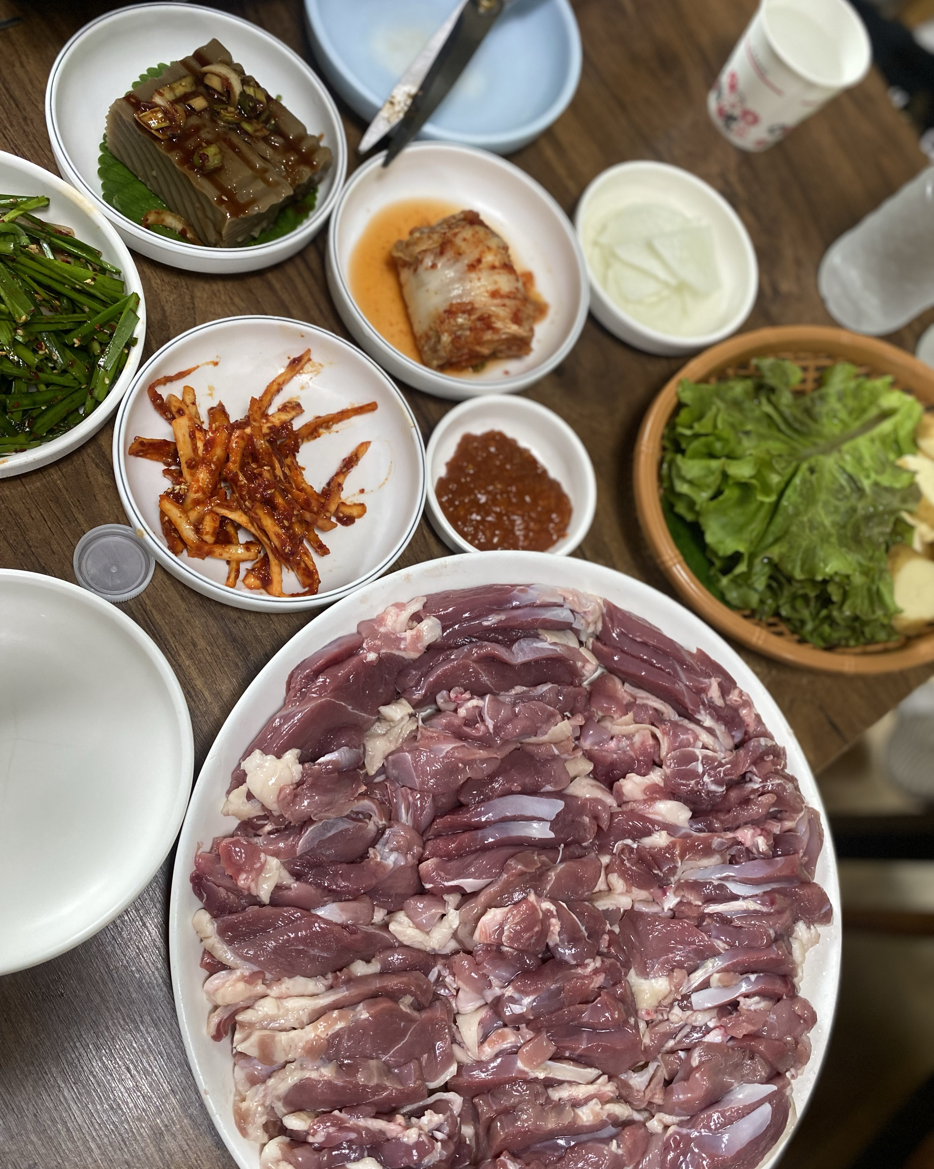 식탁 위에 놓인 쌈 채소와 마늘, 쌈장