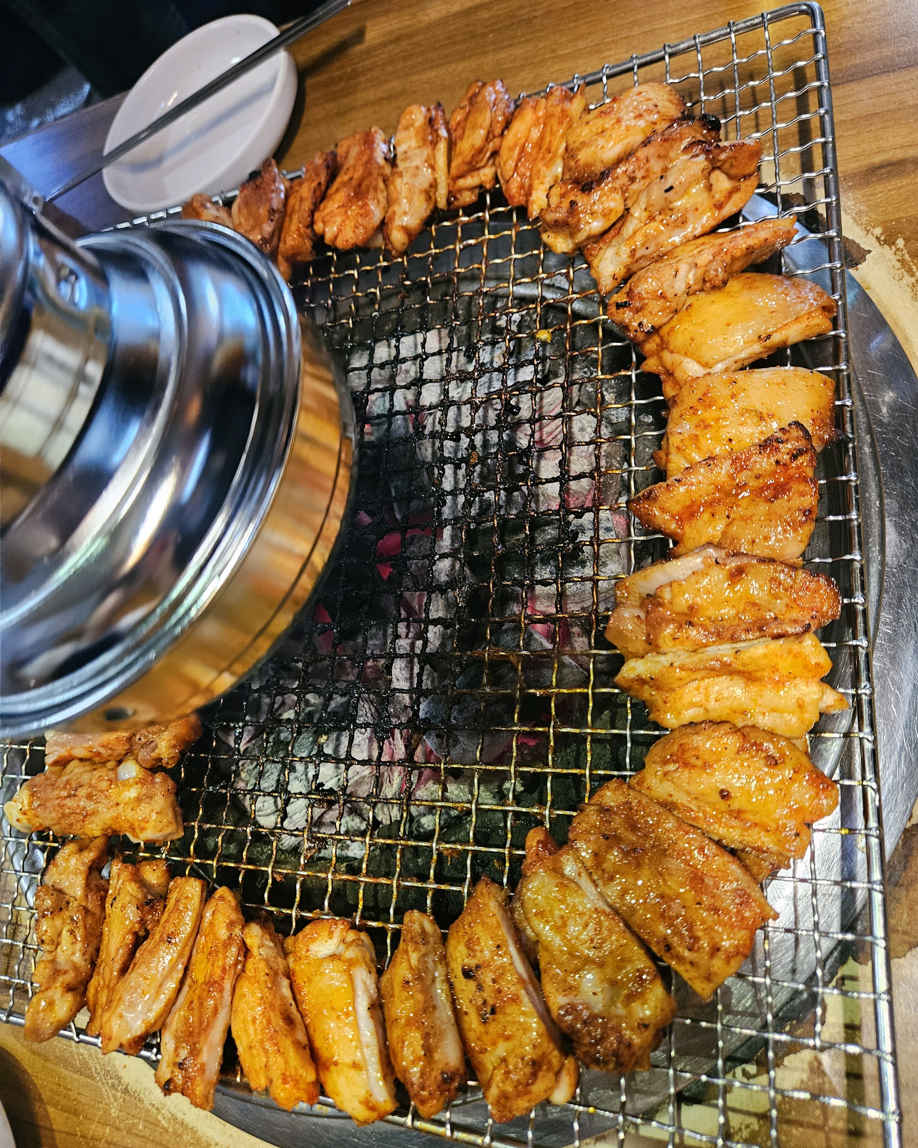 숯불 위 원형으로 놓인 양념 닭갈비와 닭목살