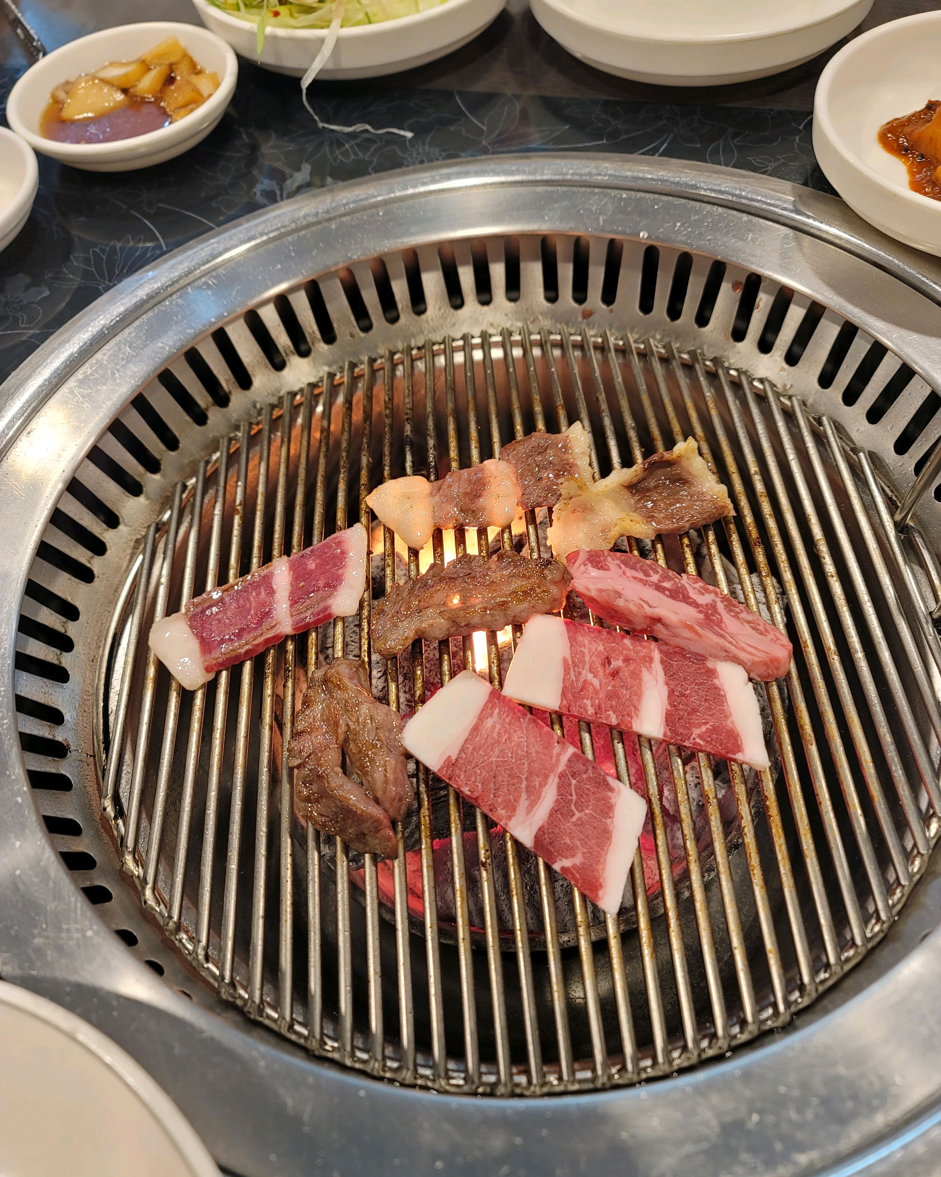 불판 위에서 익어가고 있는 다양한 부위의 소고기