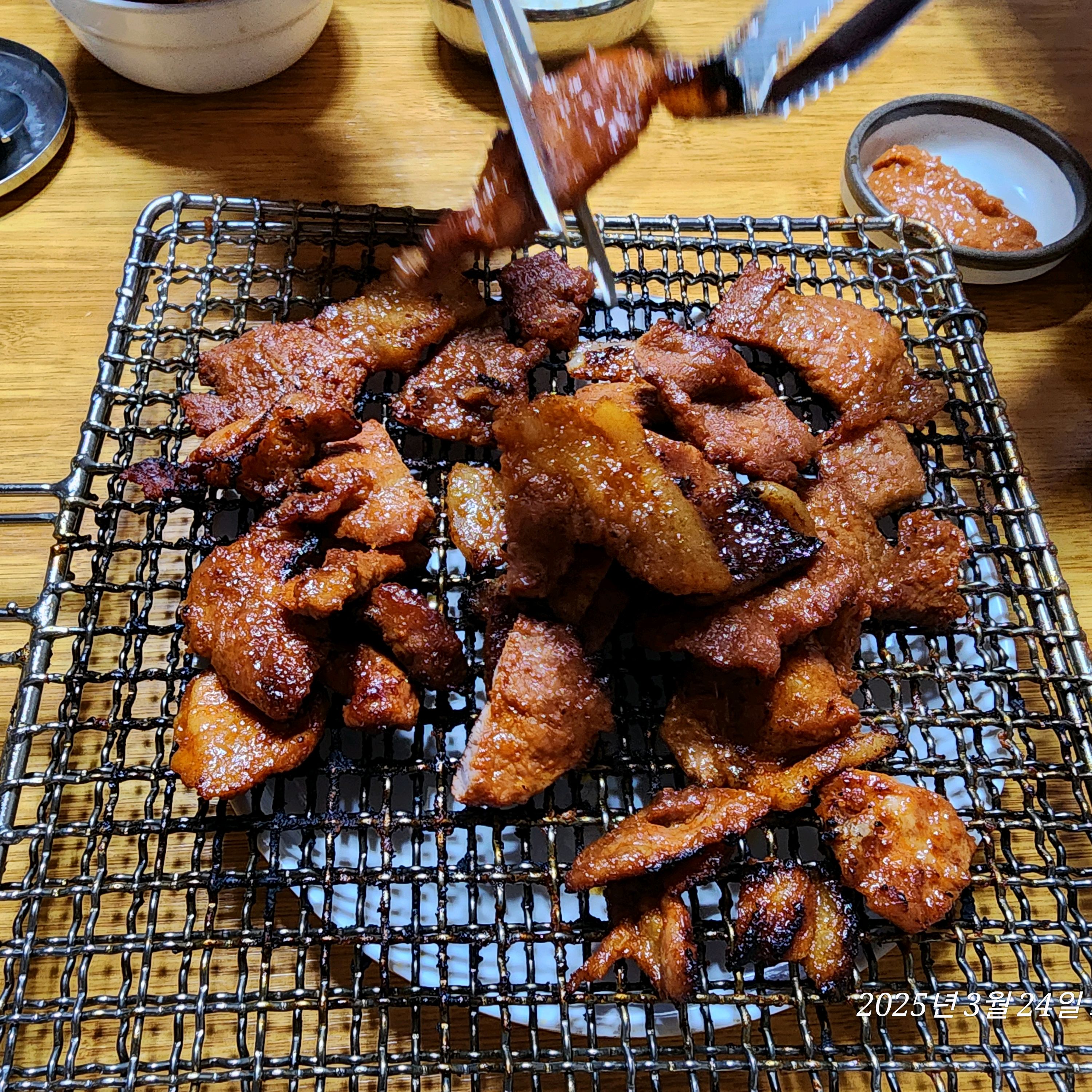 집게로 집어 올리는 따끈한 석쇠구이 한 점