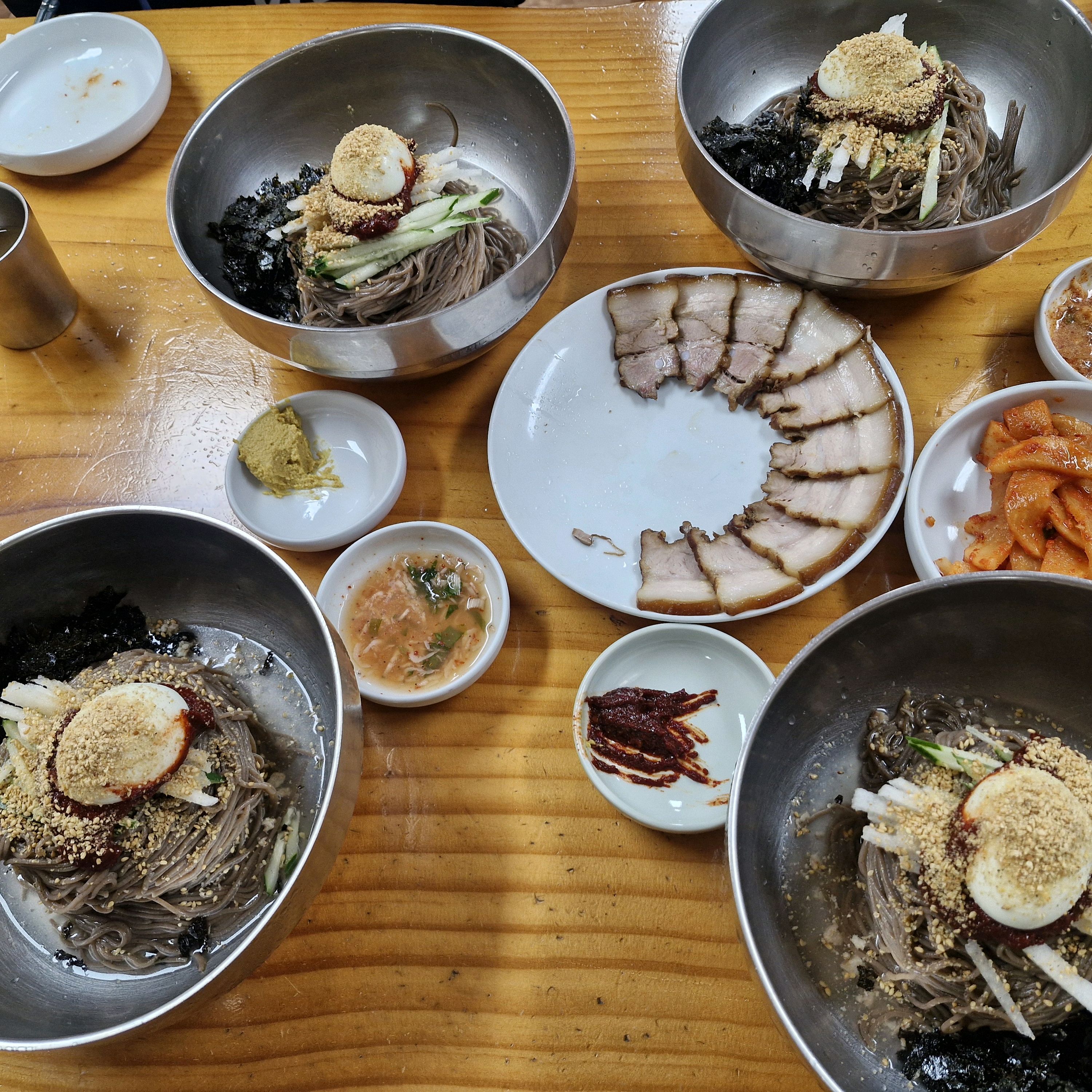 메밀면이 쫄깃하게 엉켜 있는 비빔막국수. 빨간 양념과 고명이 섞여 있습니다.