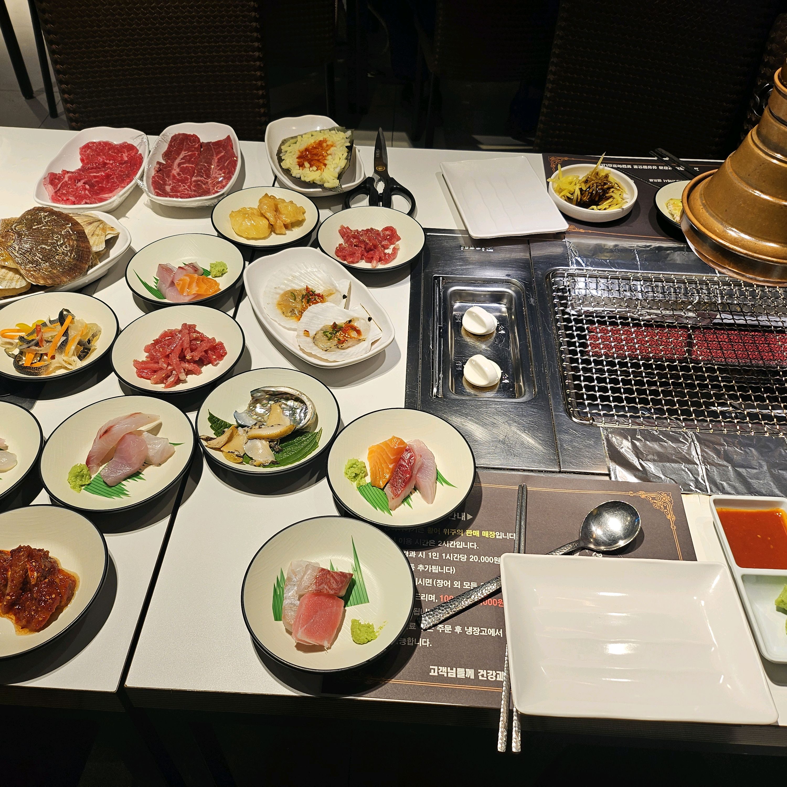 다양한 해산물과 초밥, 고기 등이 테이블에 세팅되어 있습니다.