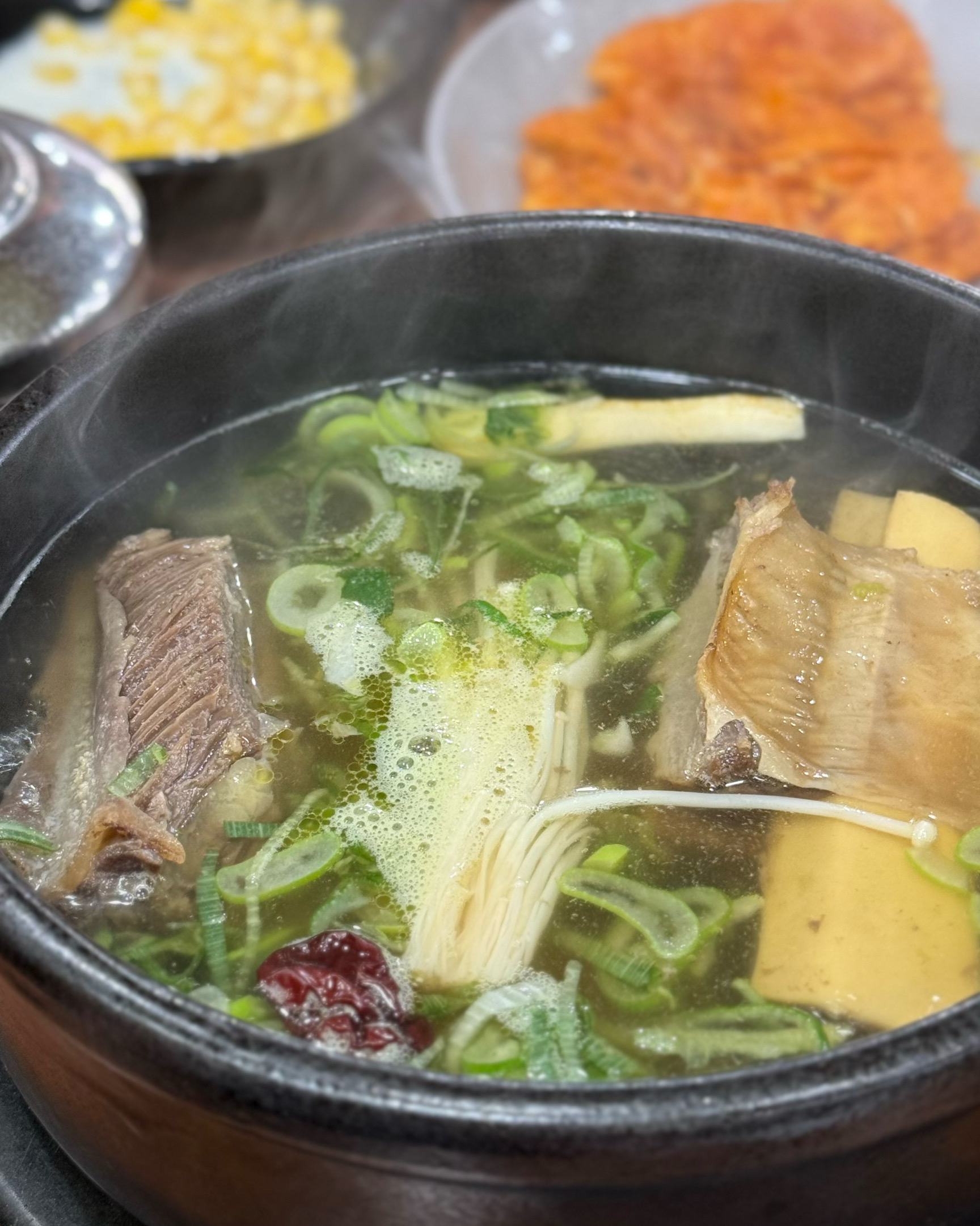 테이블에 놓인 왕갈비탕, 김치전, 깍두기 등의 모습