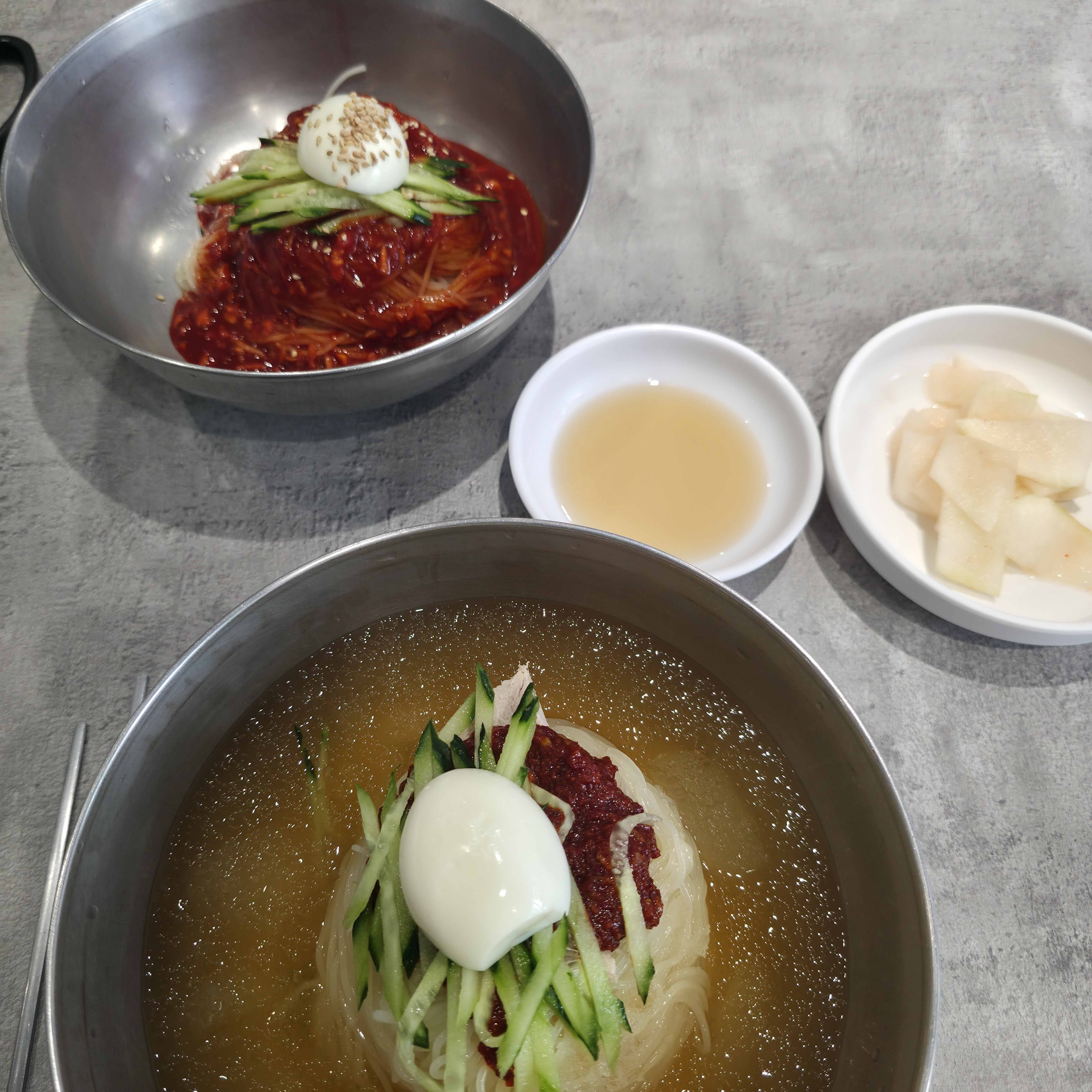 그릇에 담긴 밀면. 얇은 면발과 고명, 그리고 시원한 육수가 조화롭게 어우러져 있습니다.