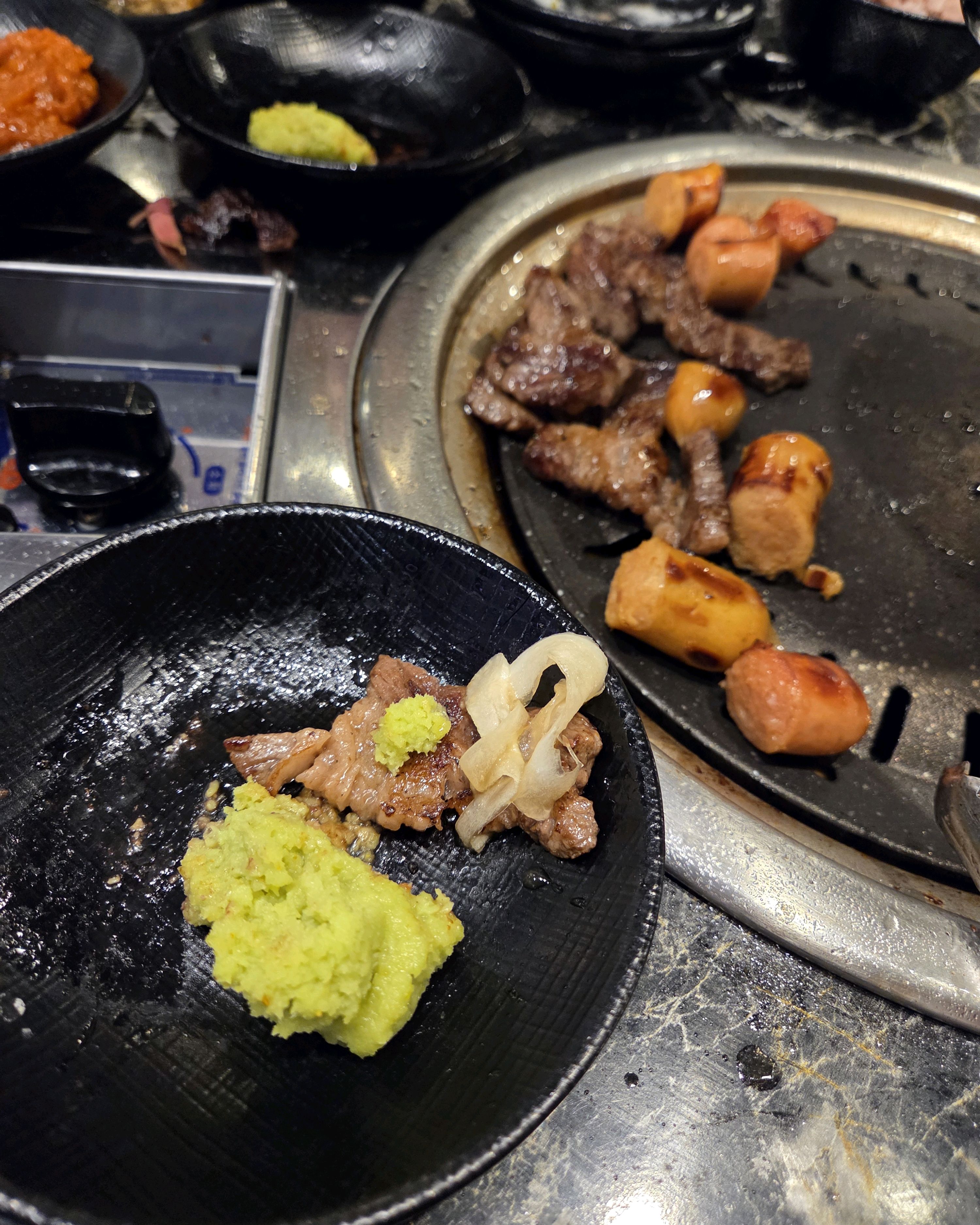 불판 위에서 구워지고 있는 고기와 소세지