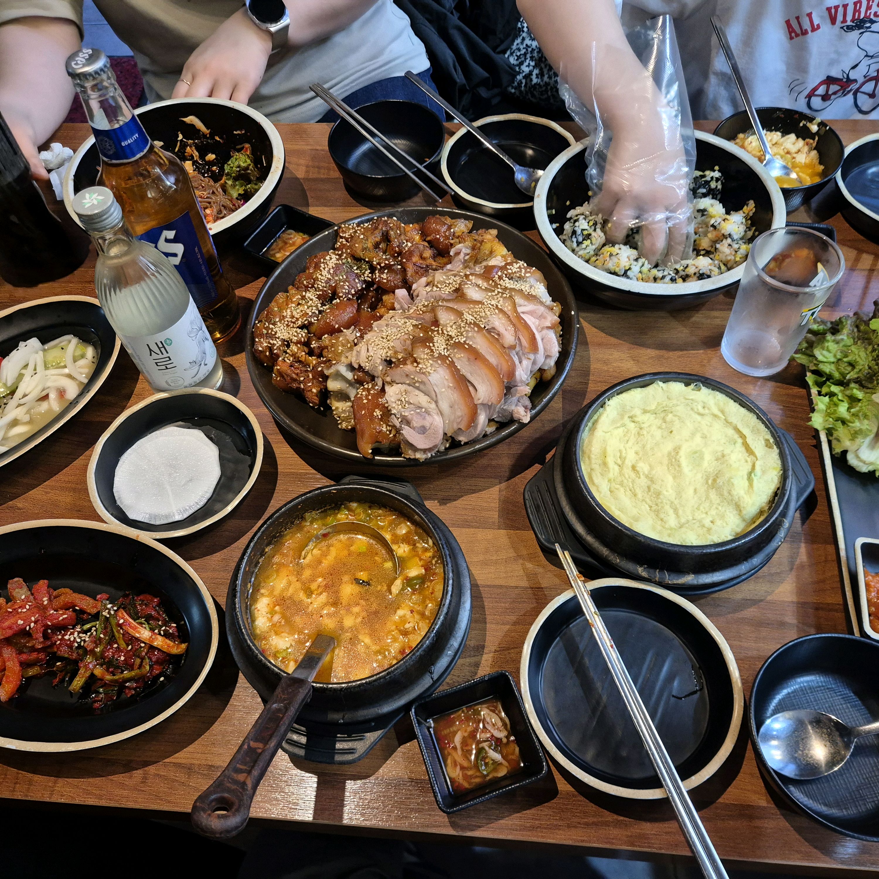 여러가지 음식들이 푸짐하게 차려져 있다. 족발, 보쌈, 주먹밥, 계란찜 등이 보인다.