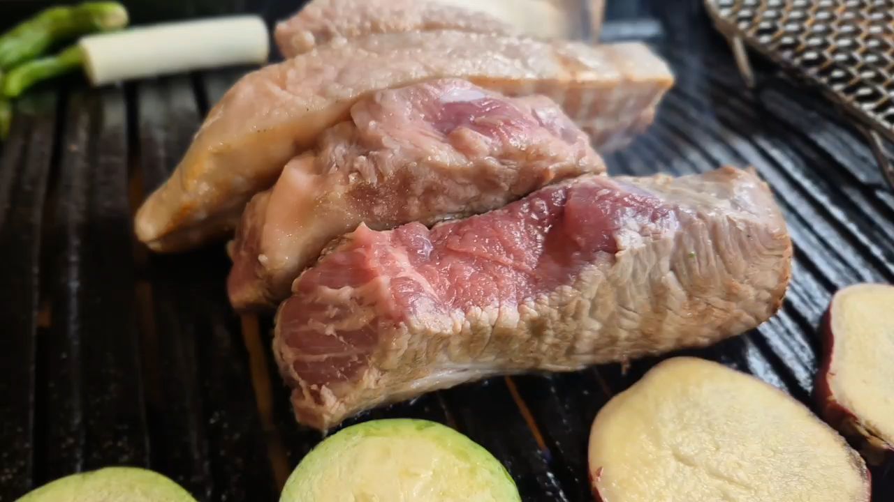 잘 구워진 삼겹살과 목살이 불판 위에 놓여 있는 모습