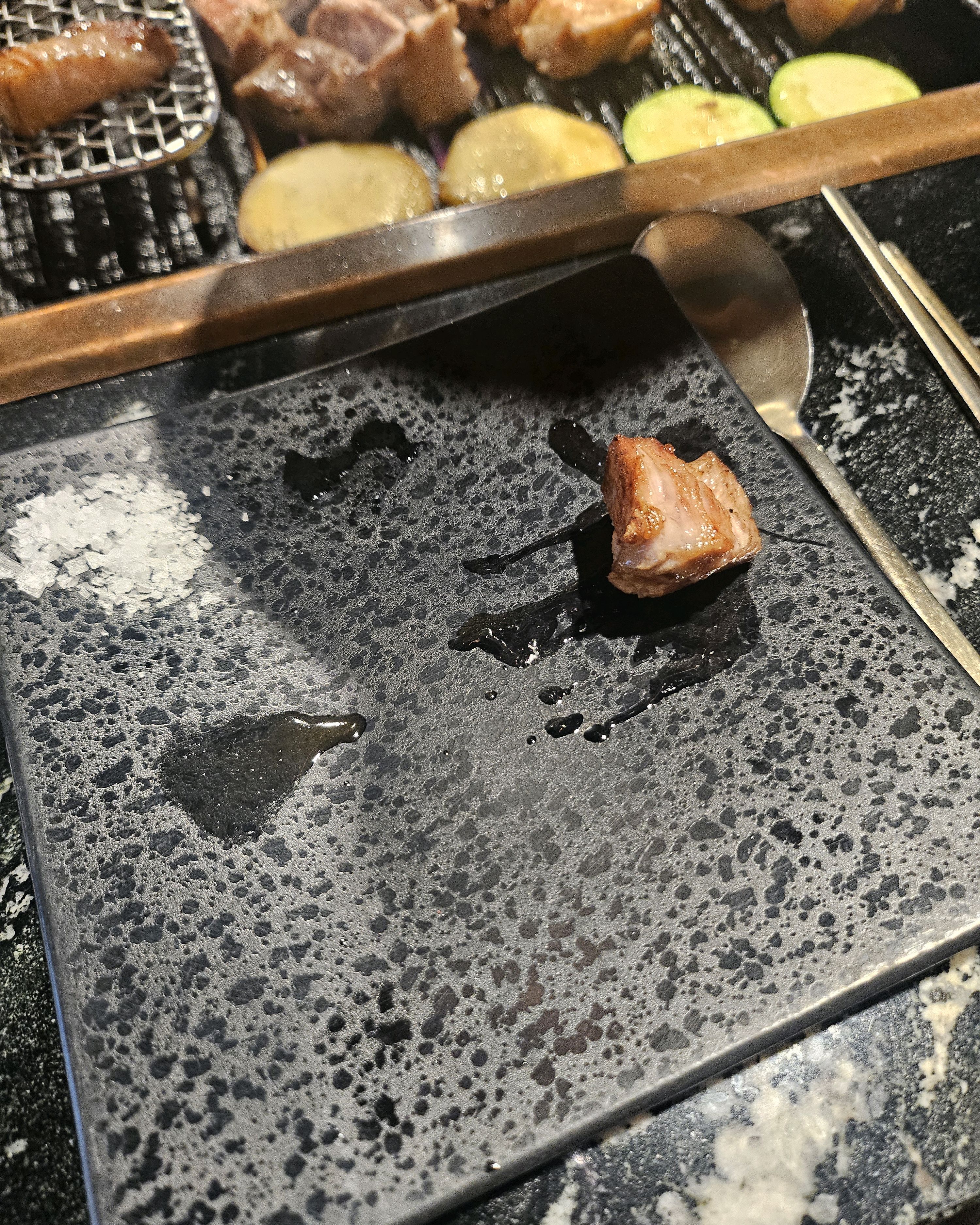 잘 구워진 고기 조각이 뜨거운 돌판 위에 놓여 있다