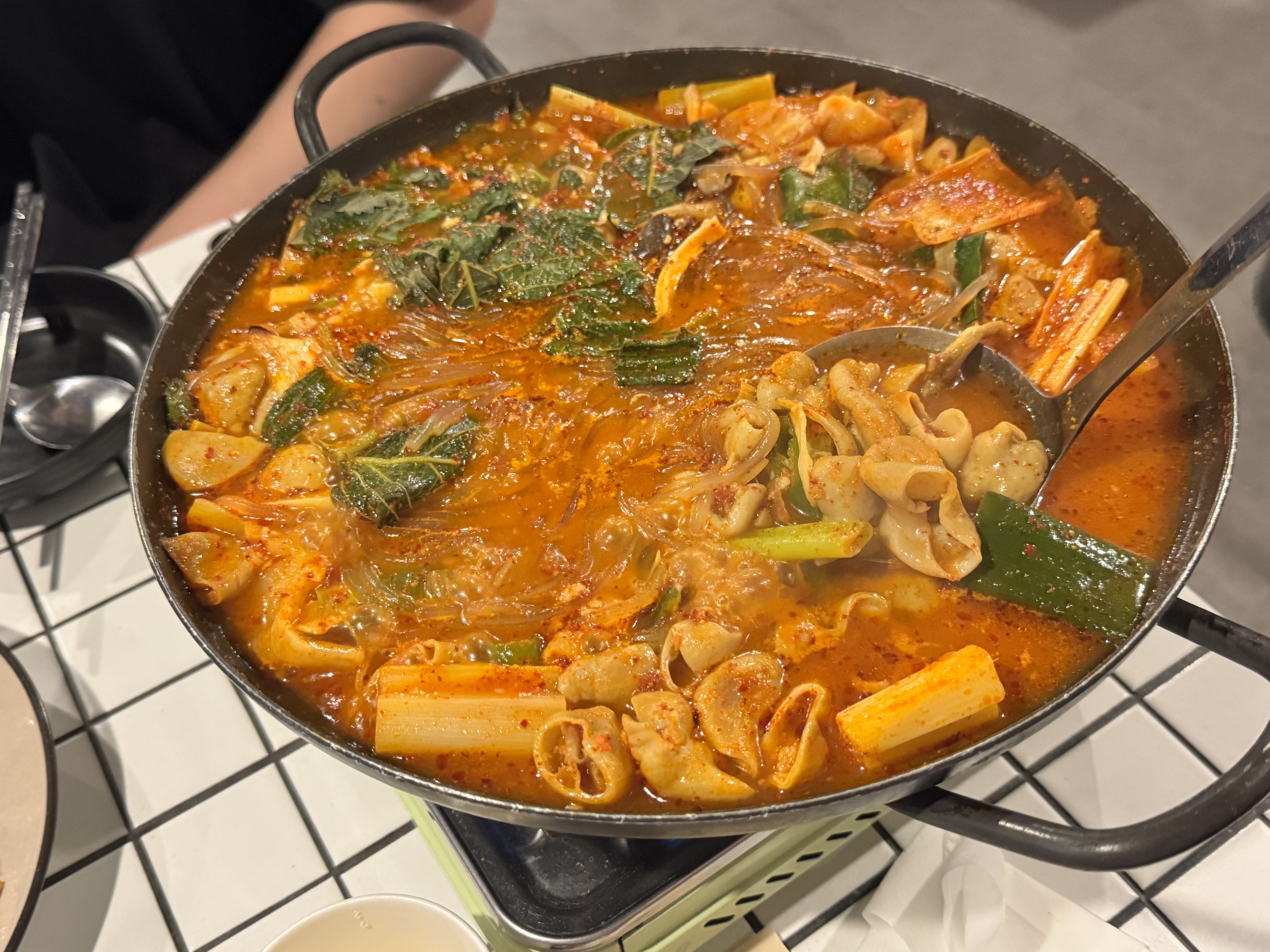 곱창전골 냄비 위로 덮인 푸른 쑥갓과 다른 채소들