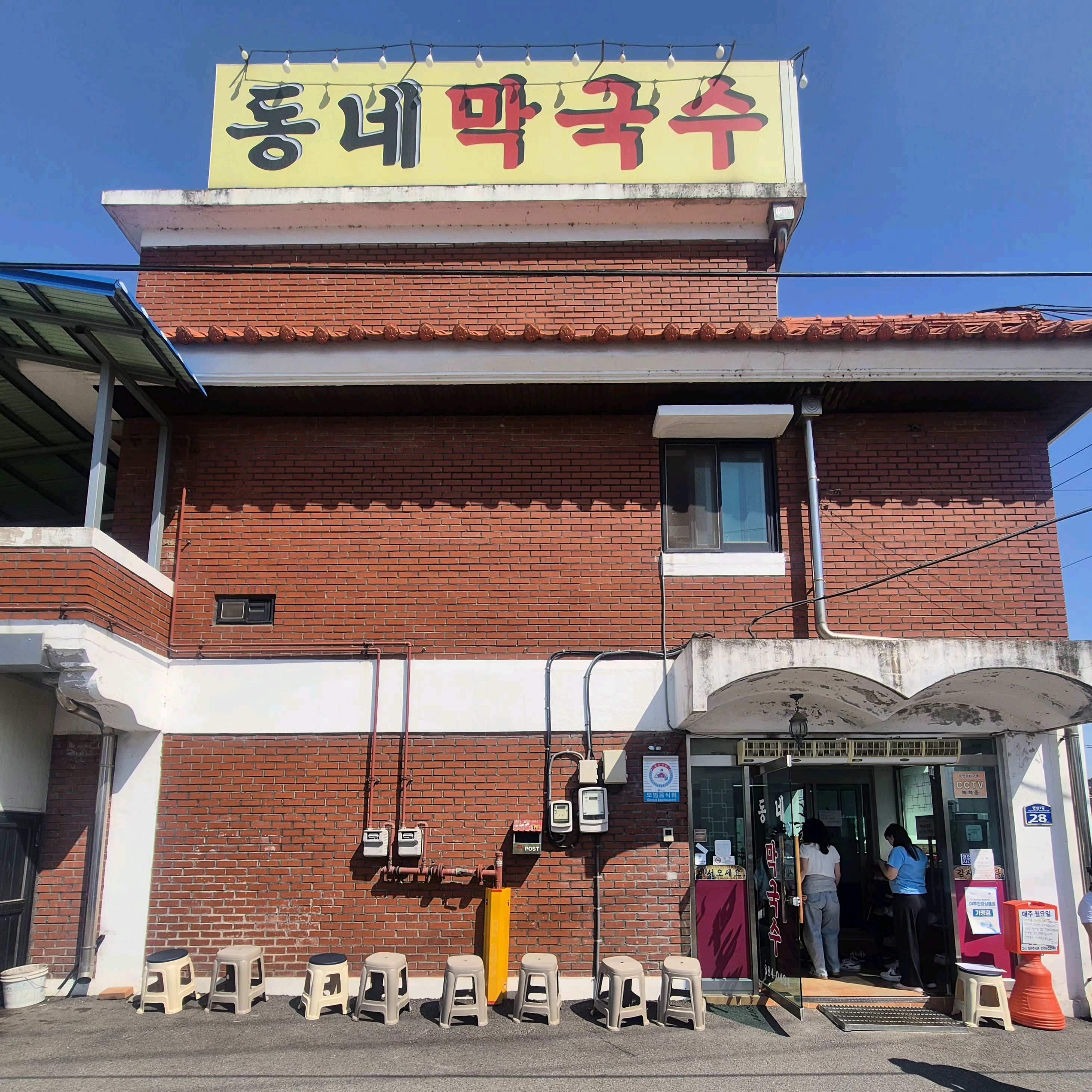 '동네 막국수' 간판이 보이는 빨간 벽돌 건물의 외관.