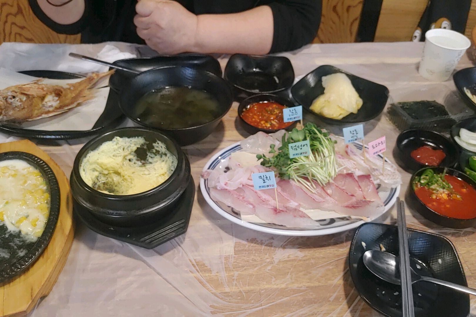 테이블에 놓인 회 접시와 다양한 밑반찬