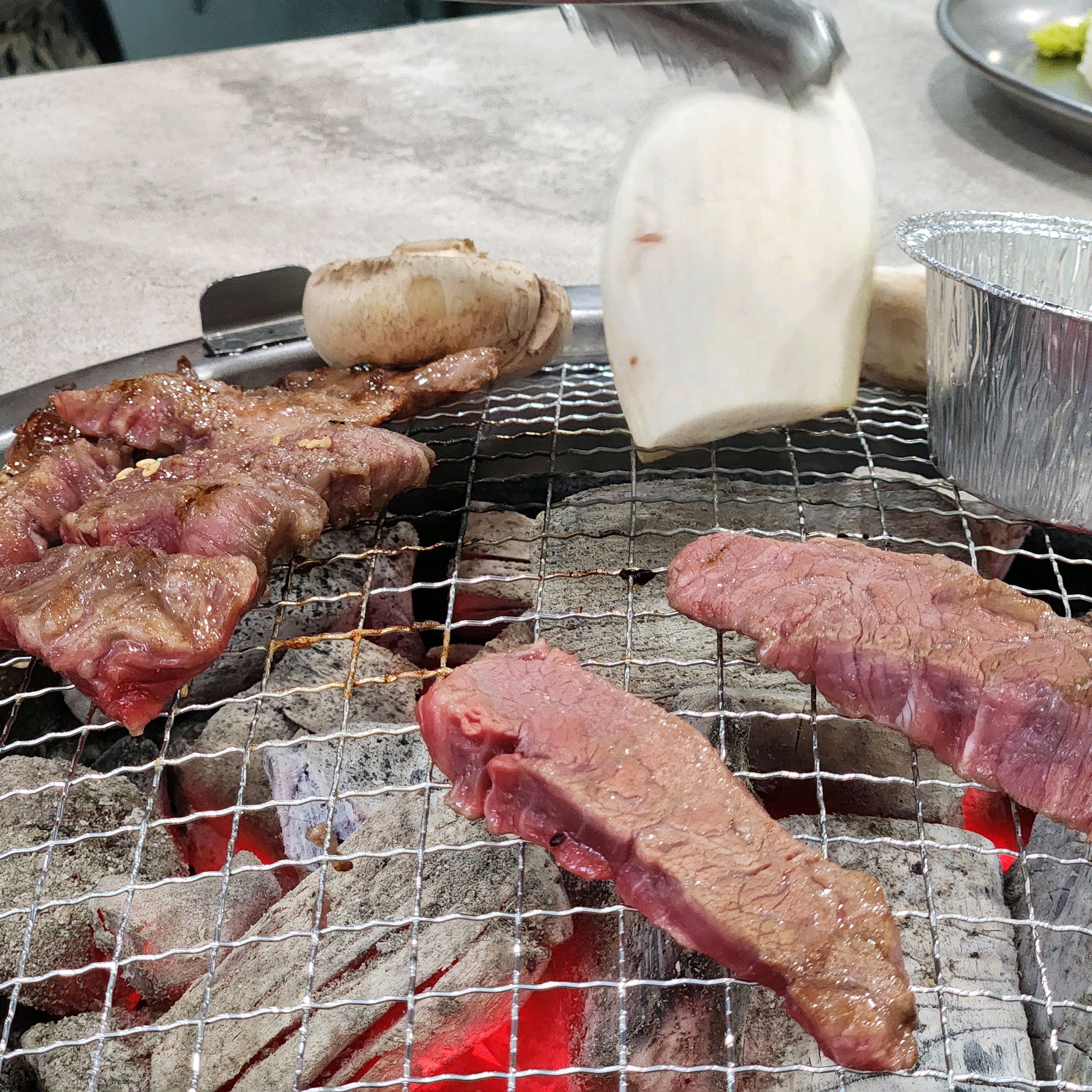숯불 위에서 익어가는 소고기와 버섯