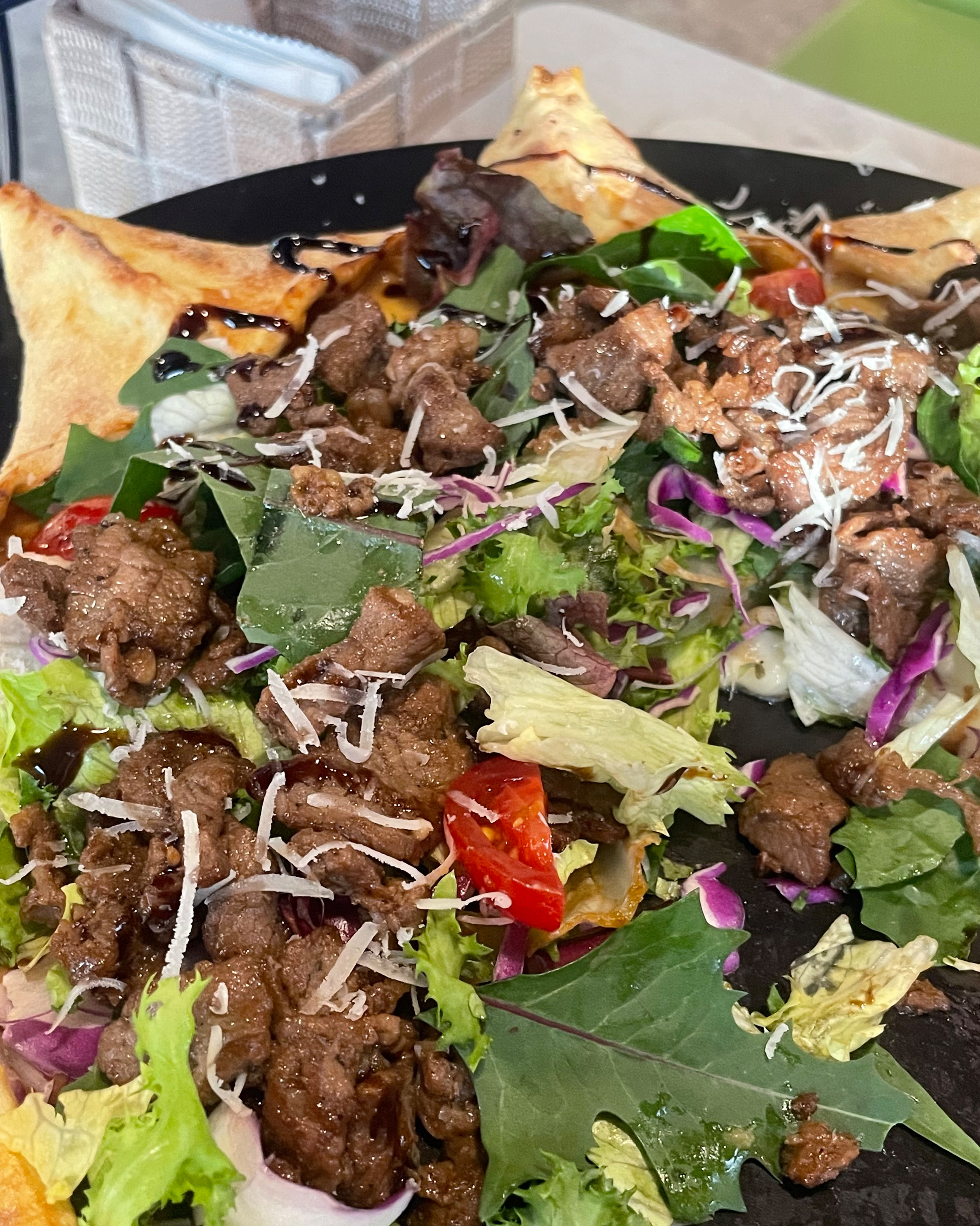 스테이크와 채소가 풍성하게 올라간 피자 또는 샐러드 사진