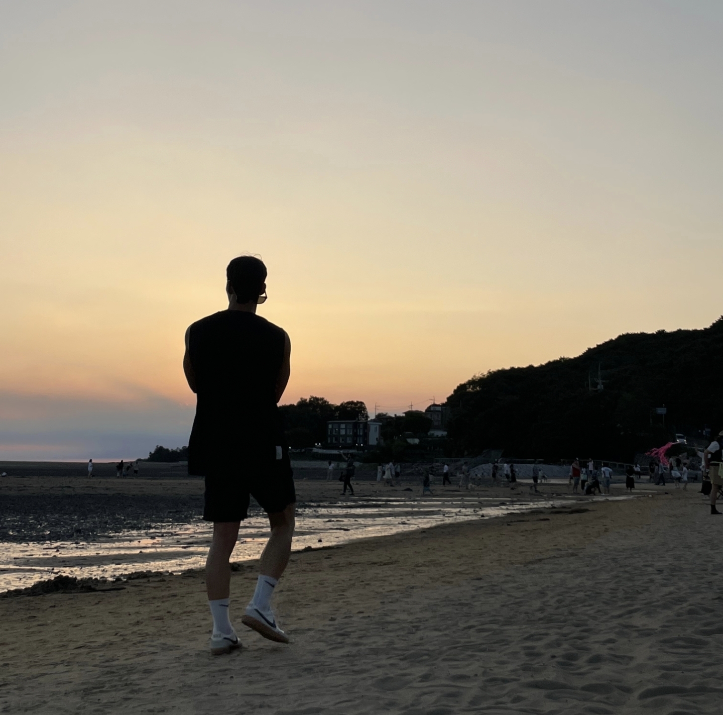 석양 아래 해변을 걷는 사람의 뒷모습