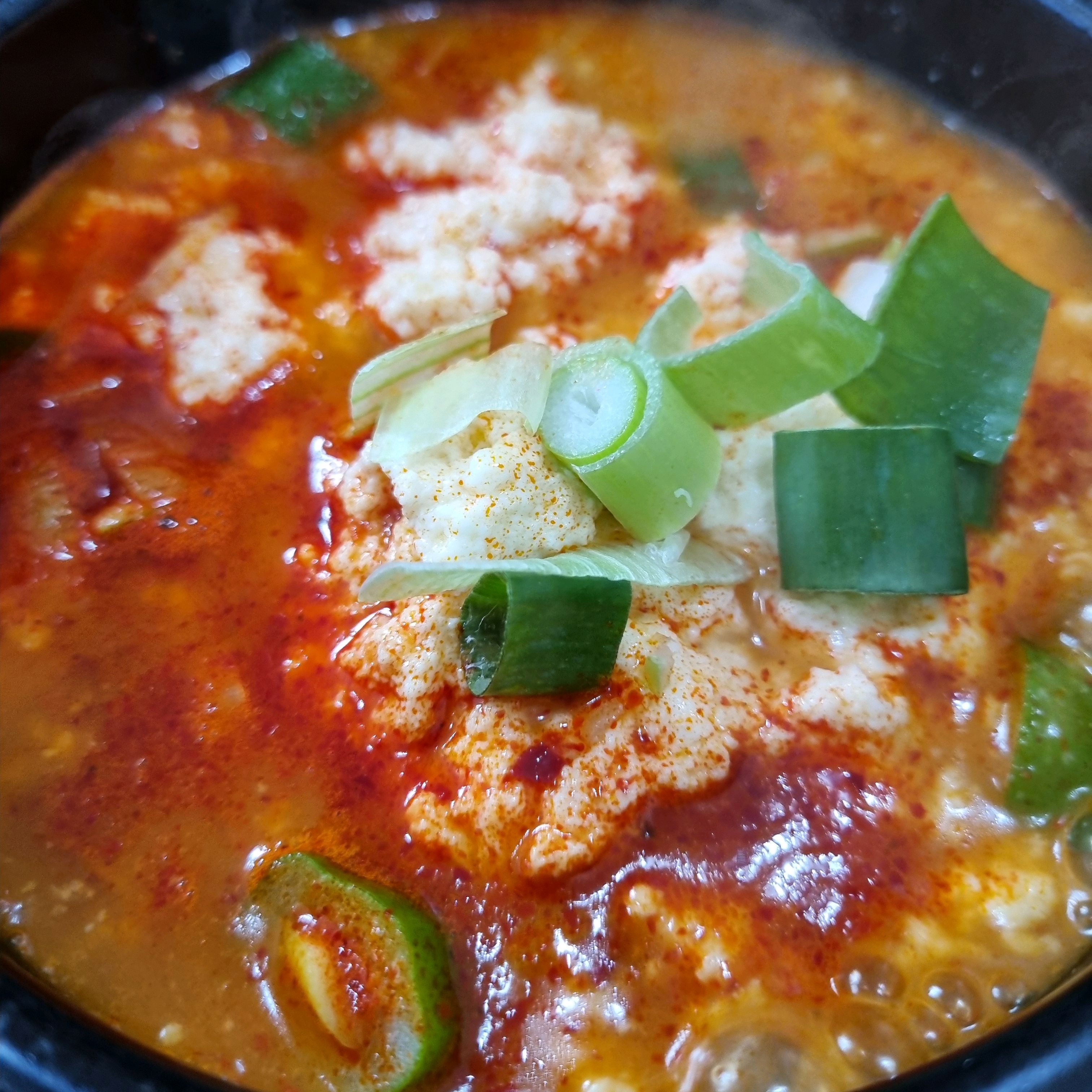 뚝배기 안에 담긴 붉은 순두부찌개와 송송 썬 대파 고명
