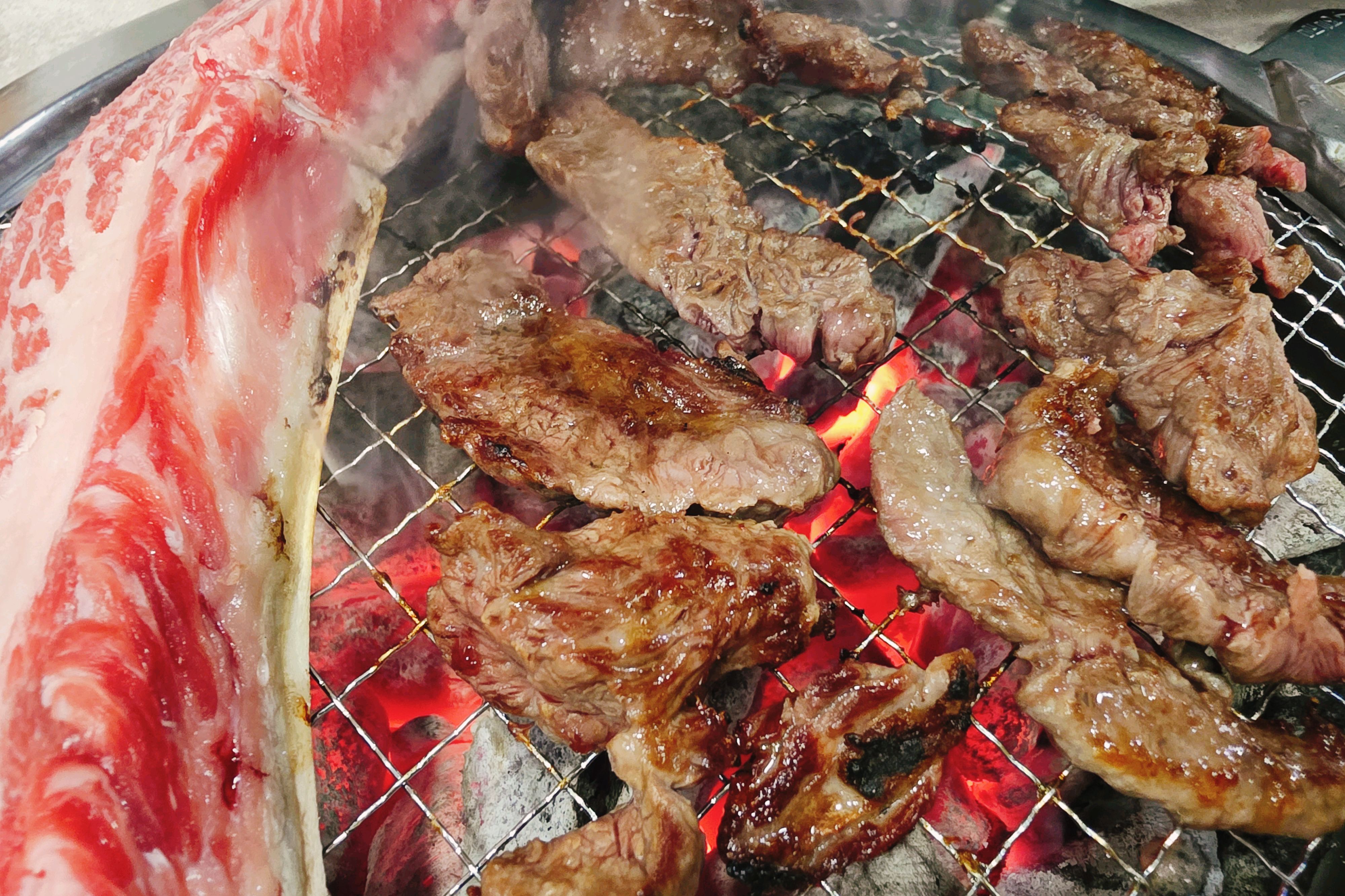 숯불 위에서 익어가는 소고기와 곁들임 채소