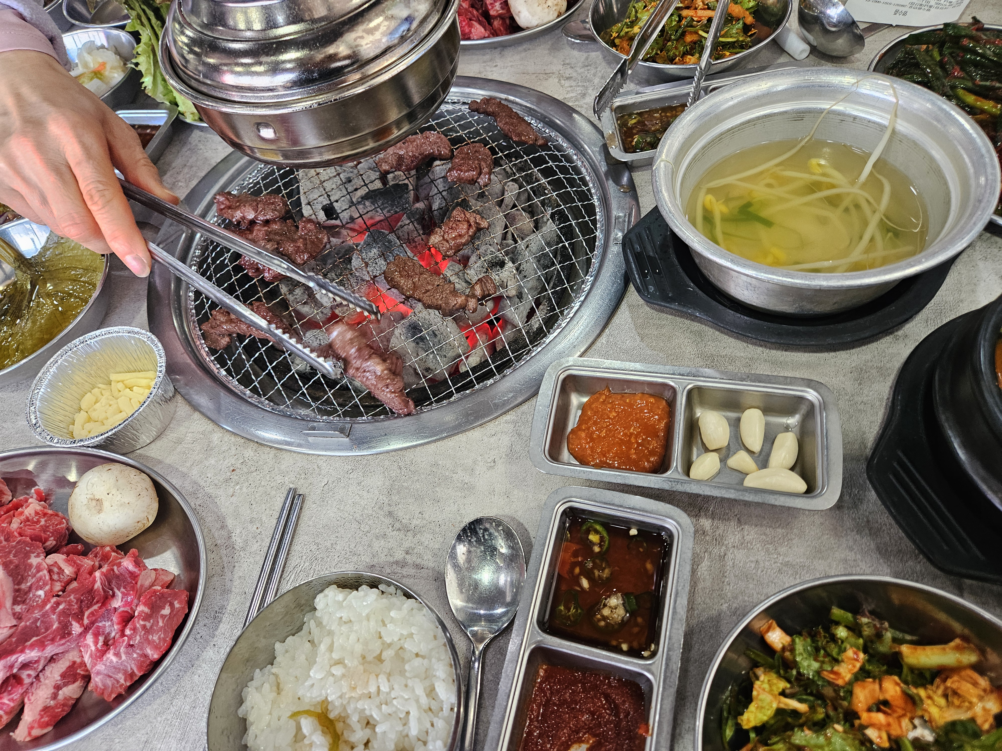 소고기 한 점을 집게로 집어드는 모습