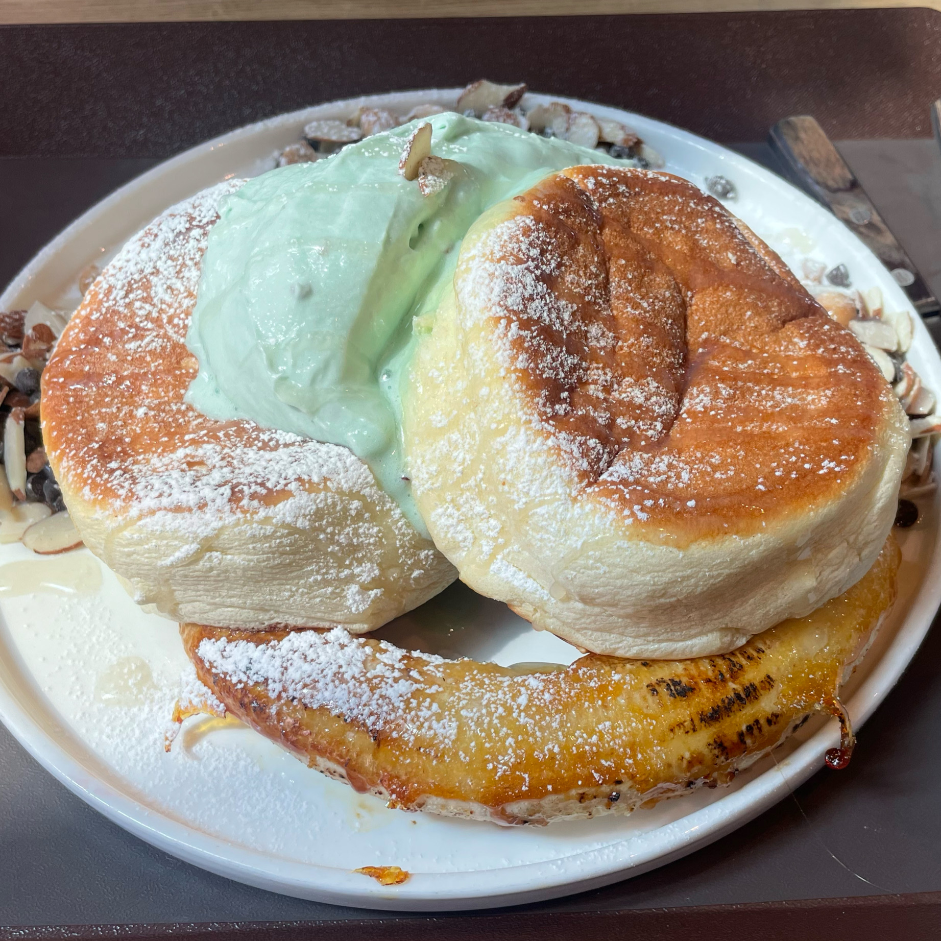 녹색 크림과 바나나가 곁들여진 젠젠 수플레 팬케이크. 독특한 비주얼이 돋보인다.